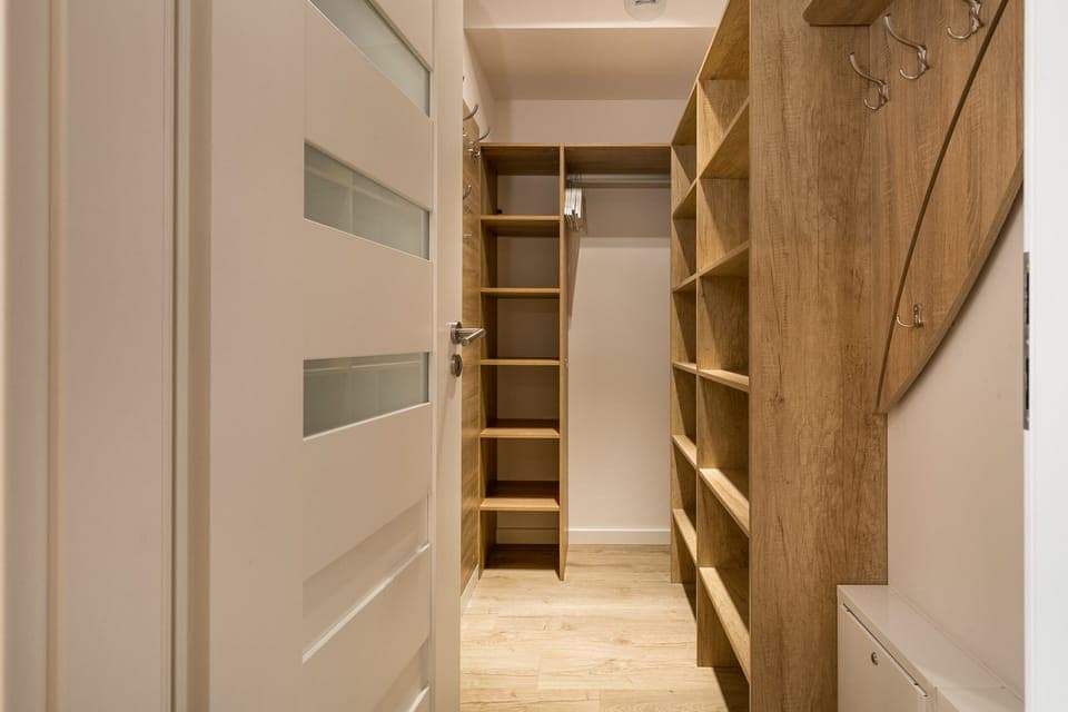 A walk-in closet with wooden shelves and a white door for organized storage.
