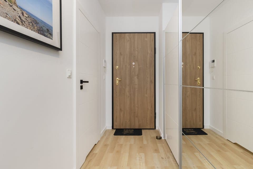 Entryway with a wooden door, large mirror, and minimalist decor, offering a welcoming first impression.

