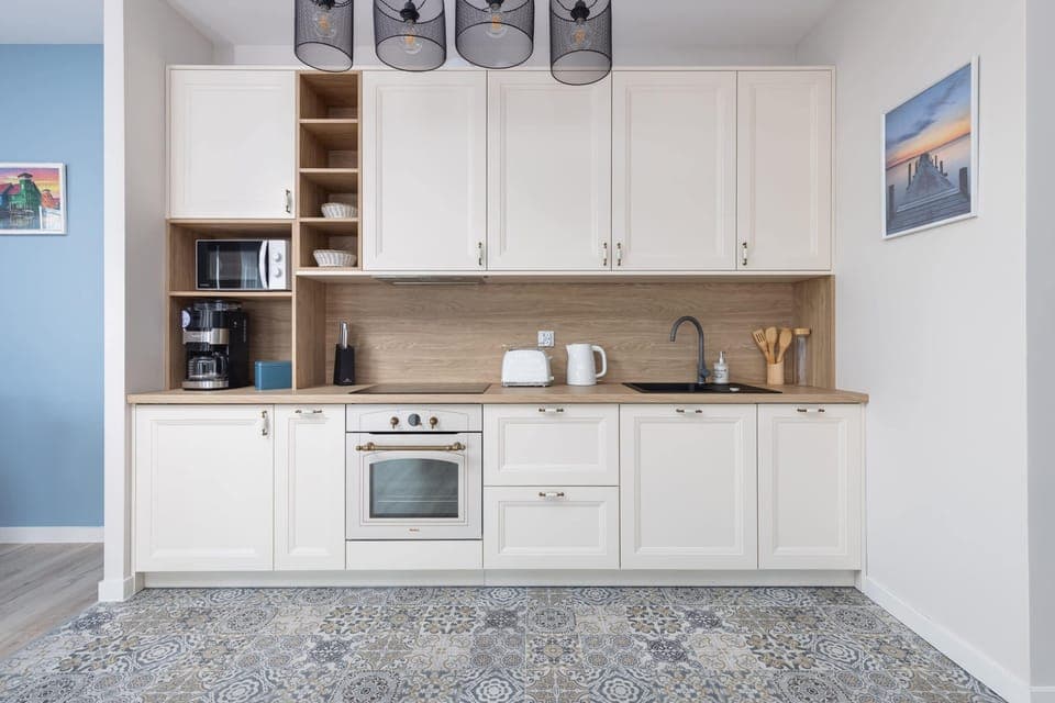 A fully equipped kitchen with white cabinetry and modern appliances.

