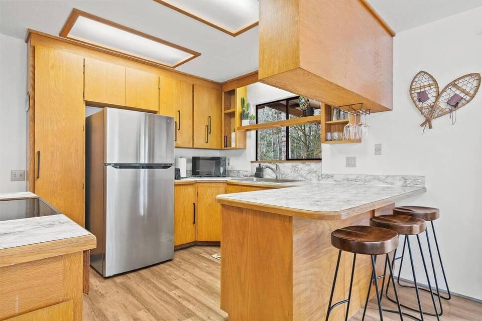 A fully stocked kitchen with all the essentials, featuring a stylish breakfast bar—perfect for morning coffee and casual meals.