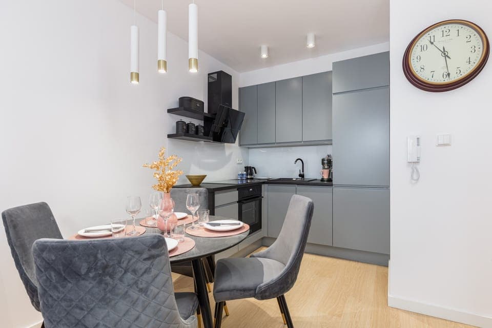 A dining area with a round table, stylish chairs, and a clock on the wall.
