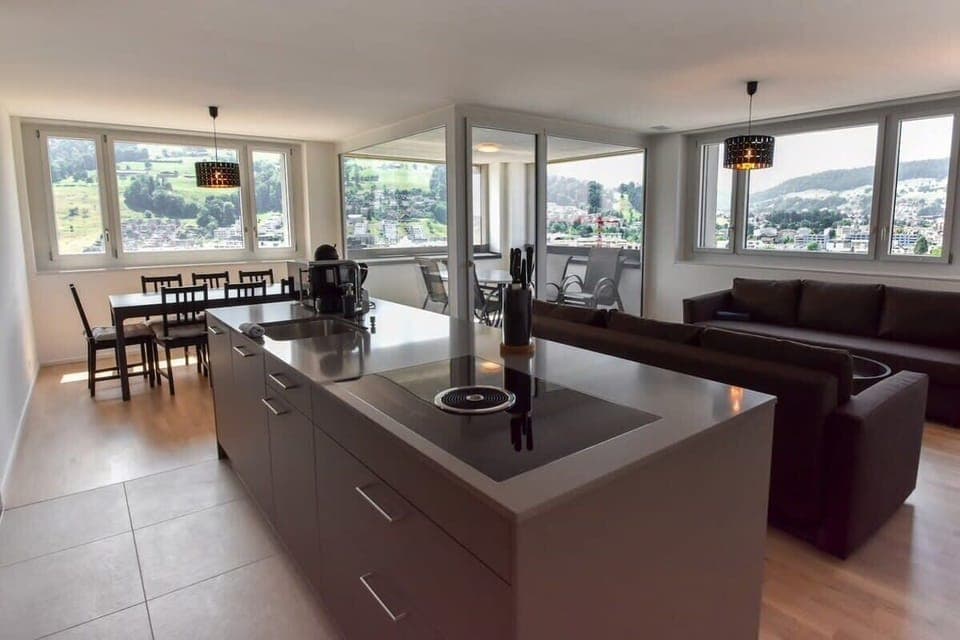 Open living area with kitchen island, dining table, and mountain views.