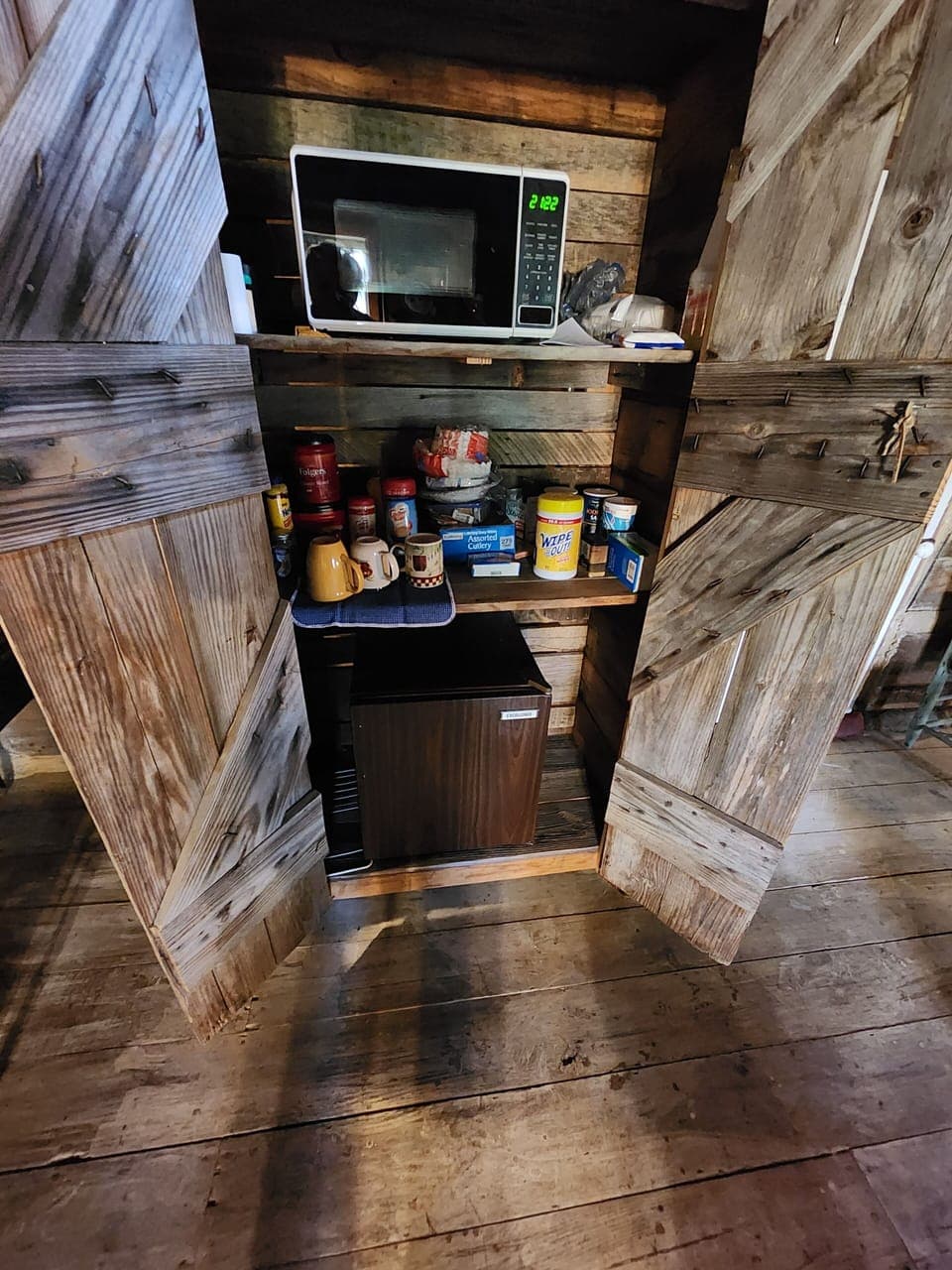 Wooden cabinet  holds microwave & Frigerator, coffee, cutlery, plates,& cups