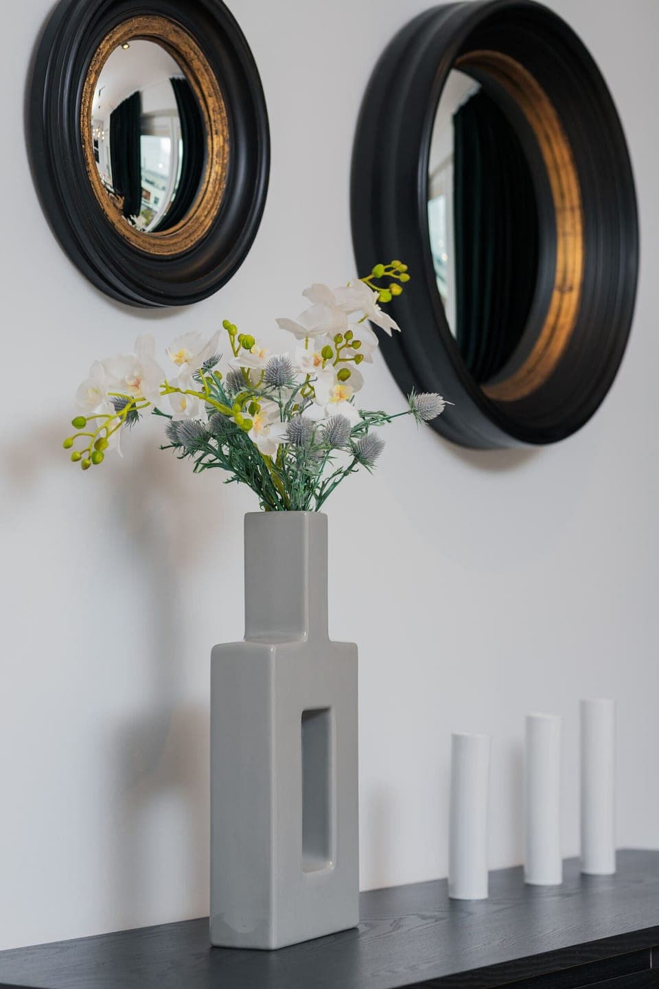 A chic vase with delicate white flowers, adding a touch of elegance to the room. It's displayed on a minimalist surface.