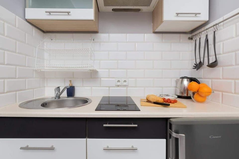 A compact kitchen with white subway tiles, dark cabinets, and essential appliances, blending functionality and style.

