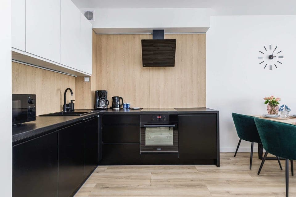 A compact kitchen with modern appliances, including a coffee maker and an electric kettle, on a light wood countertop.