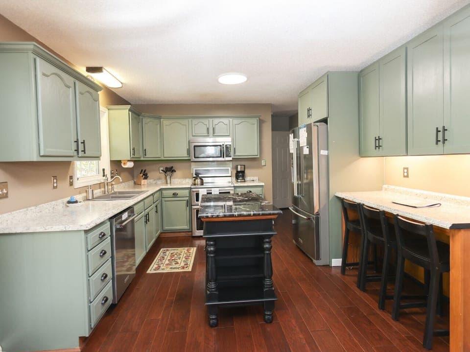 Kitchen with KitchenAid dishwasher, Crock Pot, Blender, Mixer, Drip-style coffeemaker, induction range with dual ovens, and bar seating for 3.
