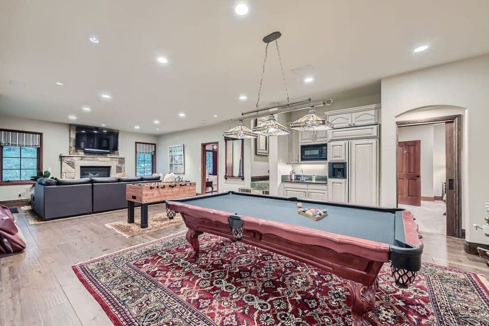 Welcome to the downstairs living room, a perfect blend of fun and relaxation! Enjoy a game of pool or foosball, cozy up by the gas fireplace, and whip up snacks in the kitchen with fridge. Easy access to the inviting hot tub for ultimate unwinding!