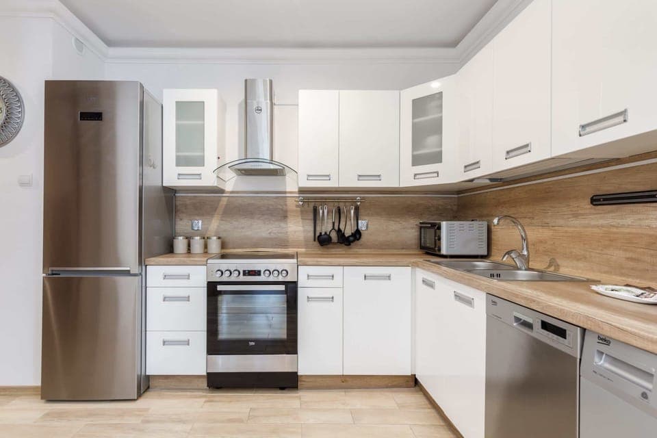 A modern kitchen with white cabinets, built-in appliances.
