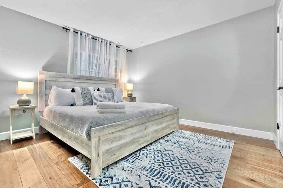 Relax in comfort with a spacious bed dressed in soft, comfy sheets and plush pillows. The bedside lamps cast a gentle, soothing glow, creating a serene atmosphere perfect for rest and relaxation.
