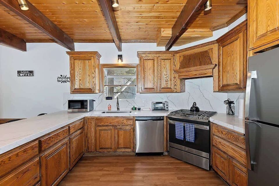 Kitchen with stove, oven, fridge/freezer, toaster oven, microwave, tea kettle, and coffee maker. 