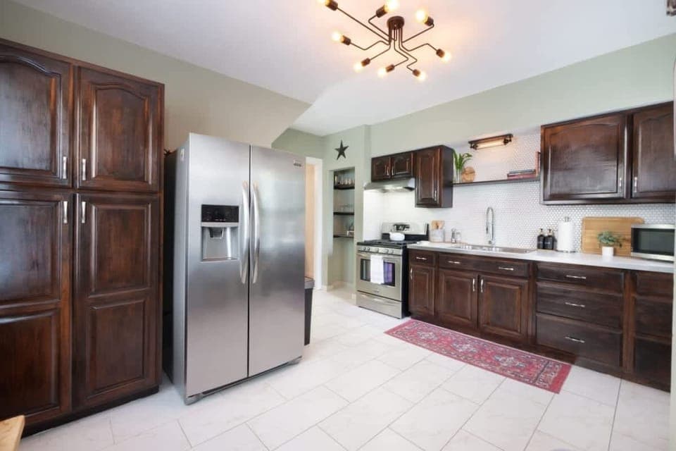Cook like a pro in this fully equipped kitchen featuring stainless steel appliances, rich wood cabinetry, and open shelving for a modern touch. Perfect for family meals or morning coffee! ☕