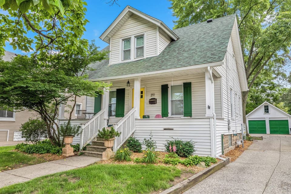 The entrance of the house adorned with a vibrant yellow door complemented by refreshing green window panels.
