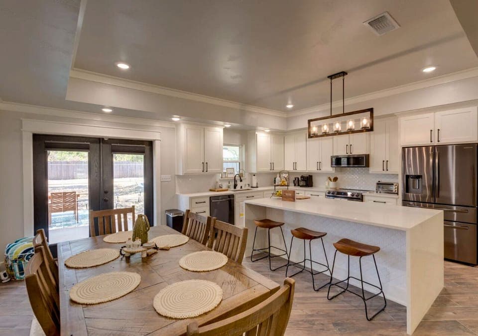 Kitchen with island, white cabinets, stainless appliances, and open dining area.