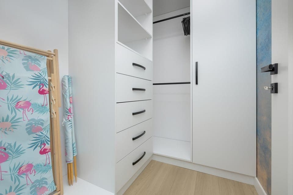A walk-in closet with ample storage, bright lighting, and a cheerful splash of color from a decorative element.

