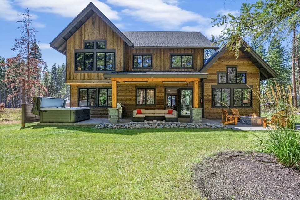 Rustic timber-frame retreat with covered porch, hot tub, and wide-open lawn