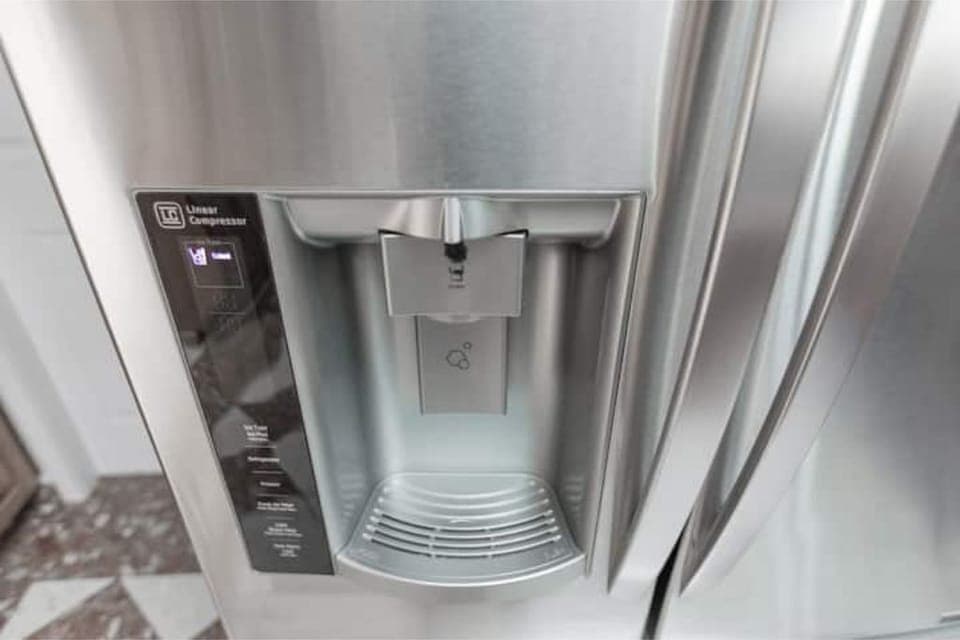 The LG stainless steel fridge has a built-in water dispenser.