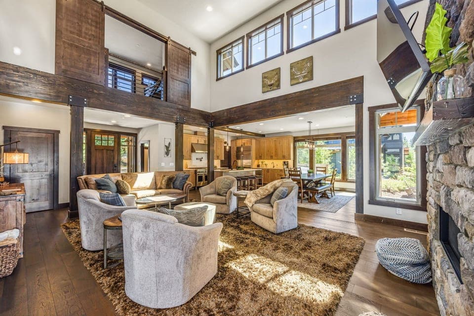 This living room is a vision of rustic elegance, featuring a towering stone fireplace, plush seating, and natural wood beams