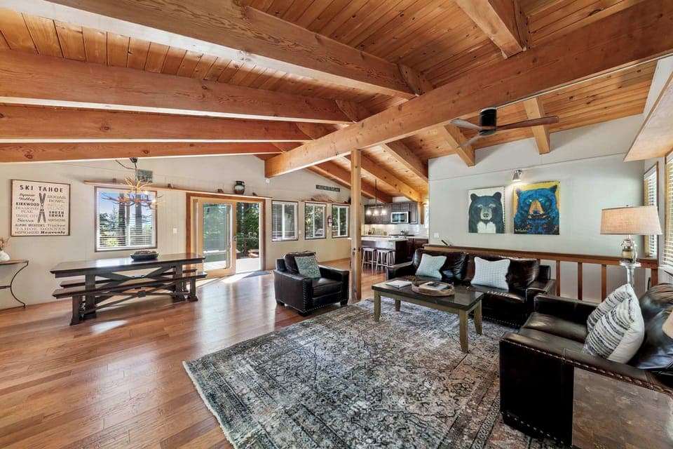Spacious, sunlit living room with warm wood beams and cozy seating—perfect for family time, games, and effortless relaxation.

