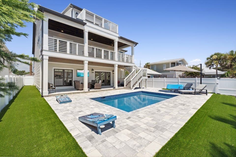 Private saltwater pool with lounge seating—perfect for relaxing after beach days, plus a fenced-in backyard & cornhole.