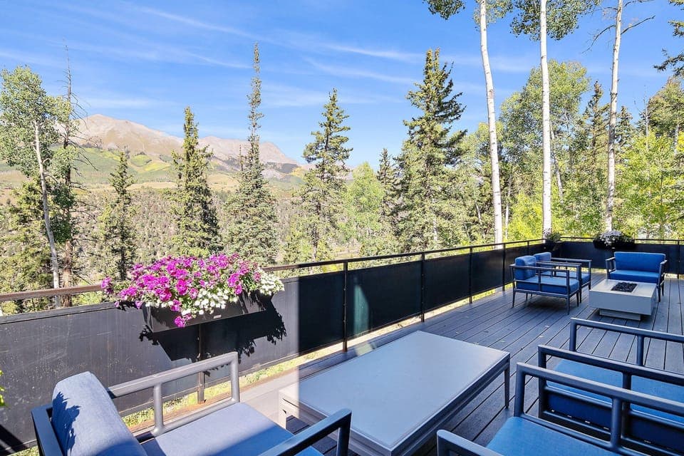 A large, spacious deck offers seating for 8+ guests, a gas fire pit, and a gas BBQ grill, all while providing stunning views and easy access to the main living level via a panoramic door—perfect for hosting and enjoying a sunset or two.