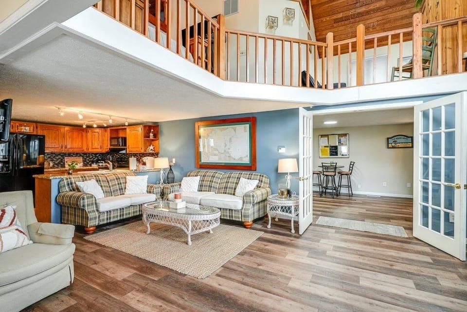 Living room with a glimpse of the gaming area and 2nd story balcony.