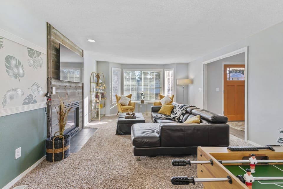 comfortable leather couch, accent chairs, decorative fireplace and  65" smart TV