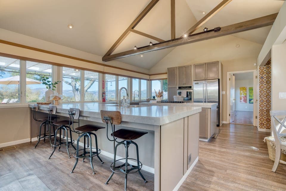 Fully-equipped kitchen with a large island, gas range, barstool seating, and a full suite of appliances.