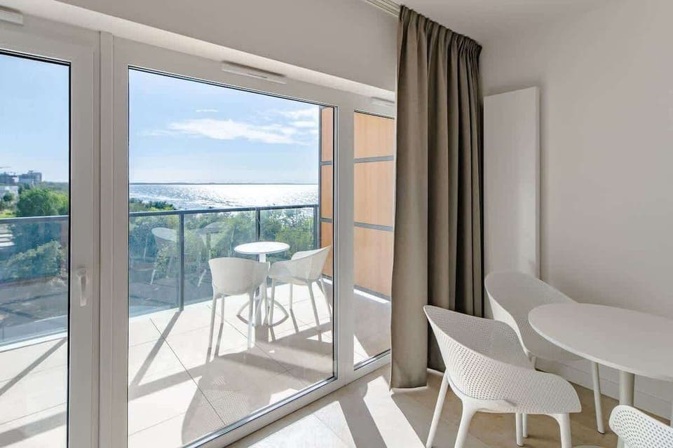 A minimalist dining area by large windows, emphasizing natural light and simplicity.
