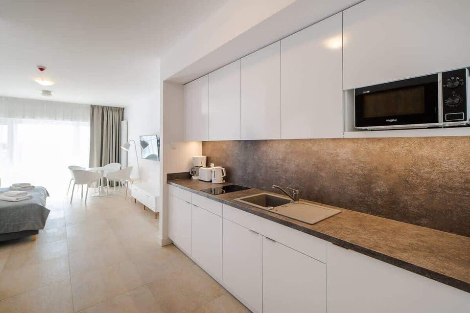 A modern kitchen with sleek white cabinets, a wooden countertop, and built-in appliances, blending functionality with elegance.
