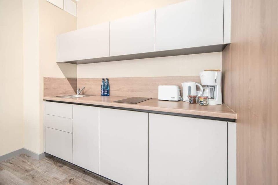 A modern kitchen with white cabinets and wooden accents, equipped with appliances for convenience and style.
