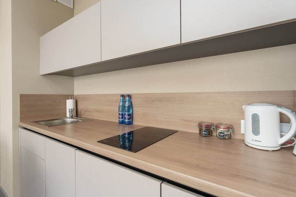 A modern kitchen with white cabinets, a wooden countertop, and appliances, blending style with functionality.
