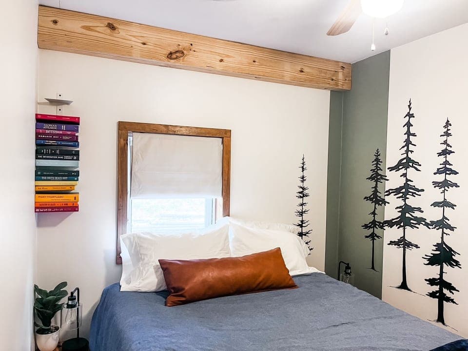 Bedroom #2 offers a cozy queen bed, whimsical hand-drawn mural trees, and easy access to the second full bathroom—just a few steps away. A peaceful retreat tucked into the heart of the cabin.