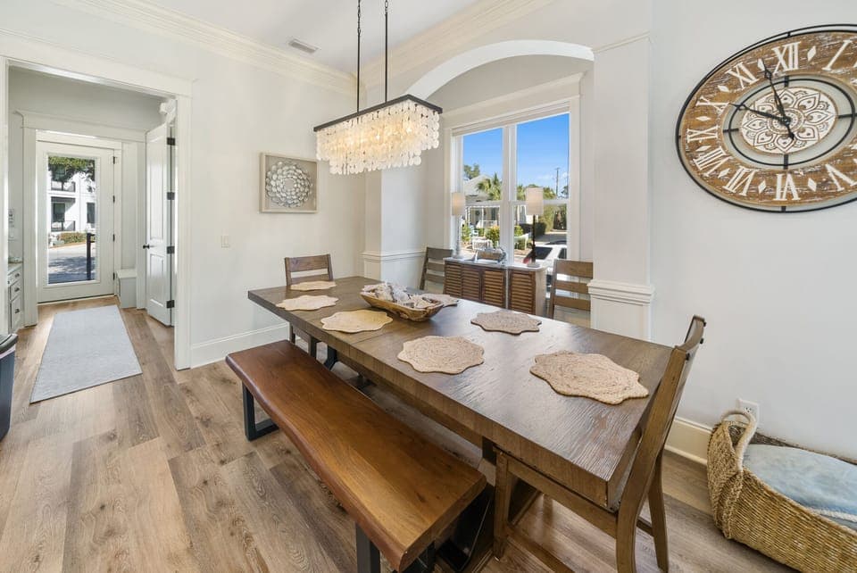 Gather around this elegant dining table where memorable meals unfold under the sparkling chandelier, with natural light streaming through arched windows.