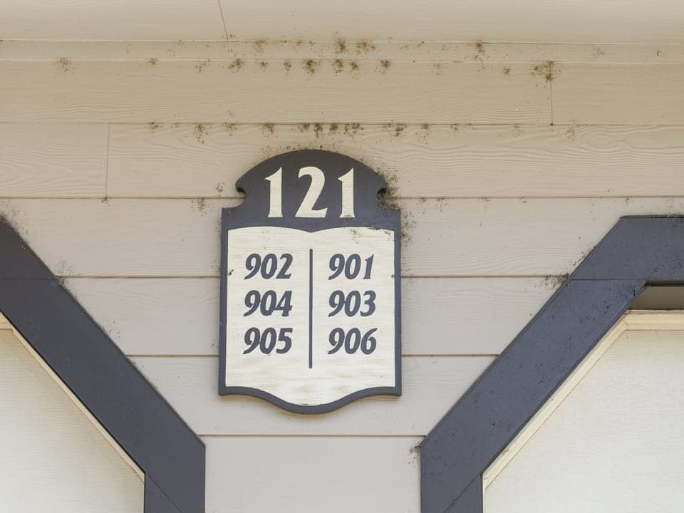 A wall-mounted directory sign at address 121, listing the following numbers: 902, 904, 905 on the left side and 901, 903, 906 on the right side, set against a beige wooden background.