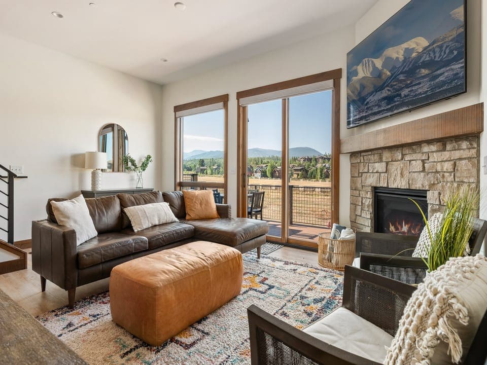 Gather in this intimate corner with a stone fireplace, flat screen TV, and mountain views - Sink into the plush sectional or enjoy a chat in the comfy accent chairs nearby - Sliding doors lead to the balcony with wide open scenic landscapes