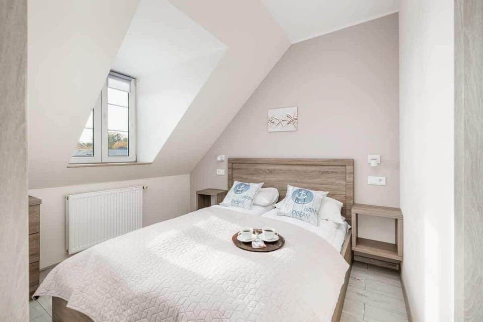 A cozy attic bedroom with a large bed, sloped ceiling, and soft lighting.

