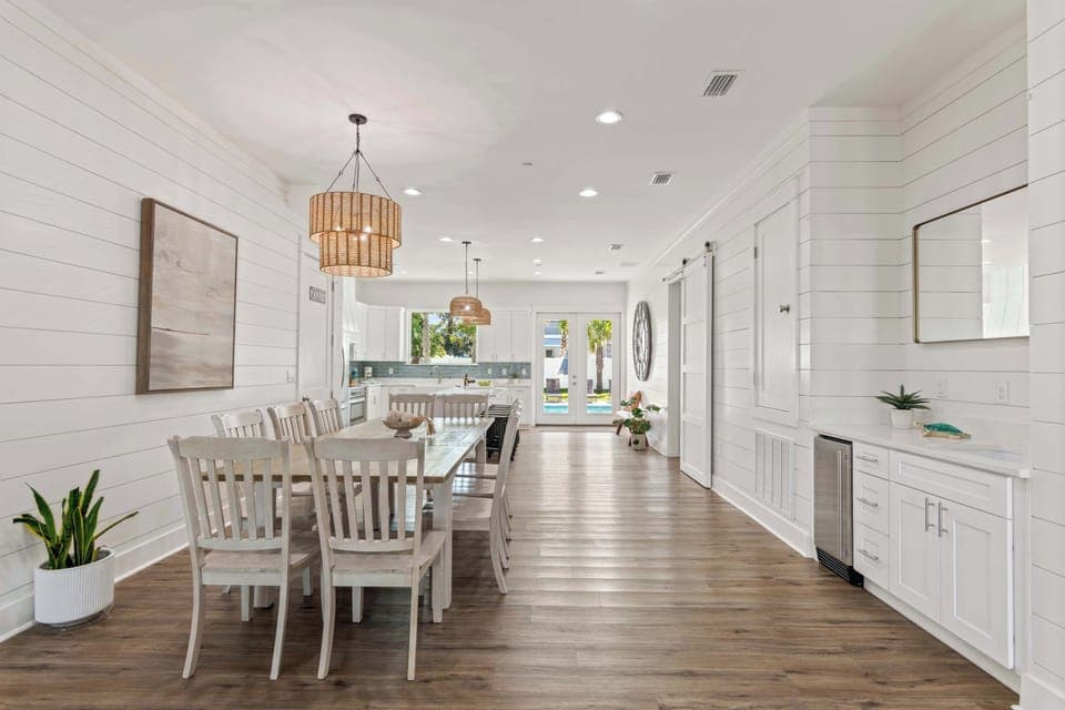 Dining room view w/ long table, pendant lights, and a bright open layout.