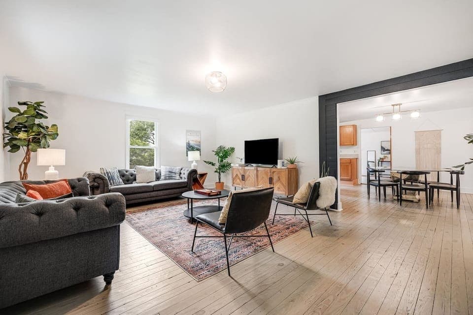 Professionally remodeled living room with two large, comfy couches, two lounge chairs, a coffee table, super fast WiFi, Roku smart TV, and open-living concept leading into kitchen