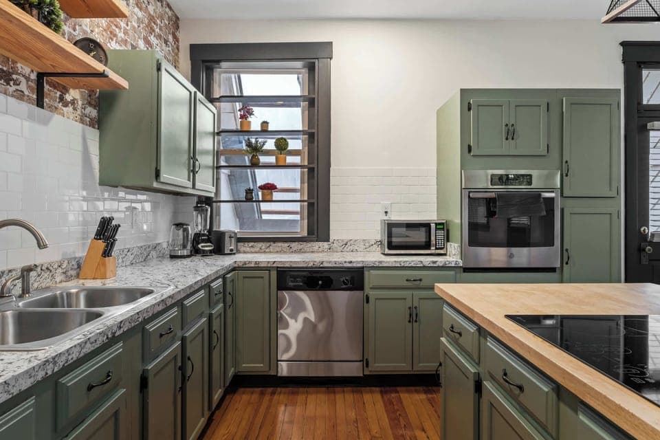 Kitchen: Our kitchen combines modern amenities with rustic charm, featuring a central island for dining and a backdrop of exposed brick.