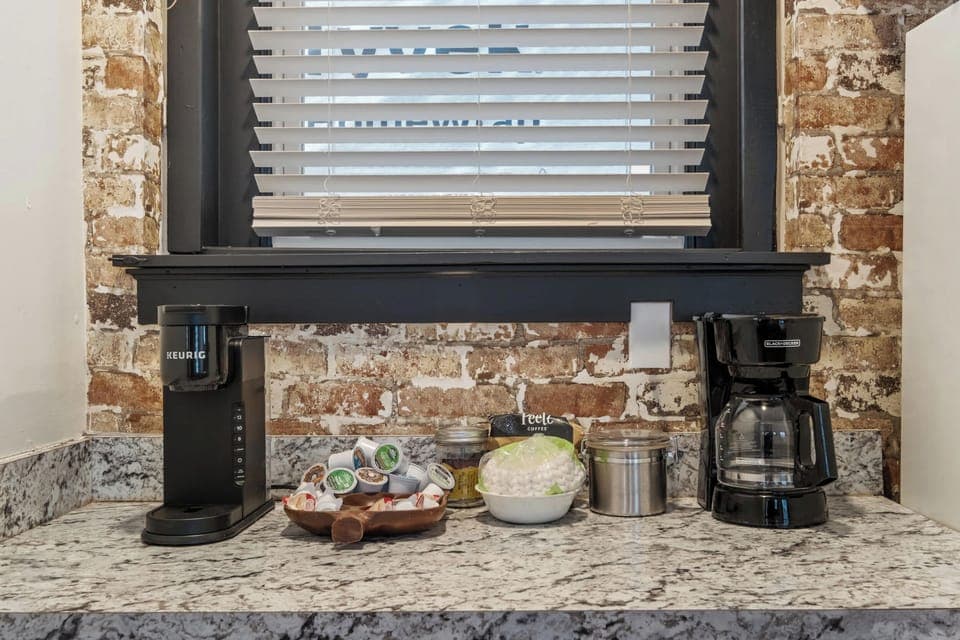 Kitchen: Our kitchen combines modern amenities with rustic charm, featuring a central island for dining and a backdrop of exposed brick.