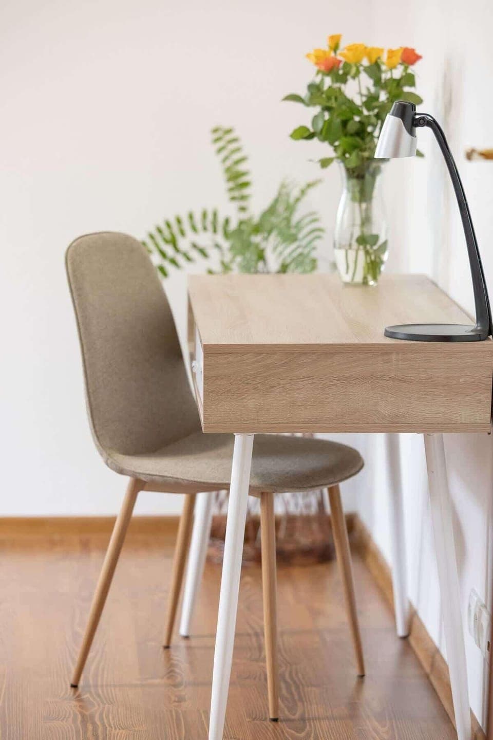 A bedroom with a grey bedspread, wooden floors, and a small table and chair, creating a comfortable and inviting sleeping area.

