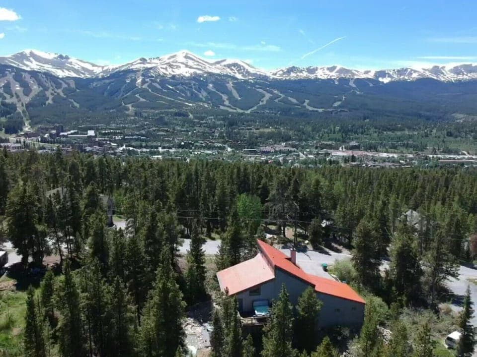 Drone view of back of the home with hot tub and the mountains.