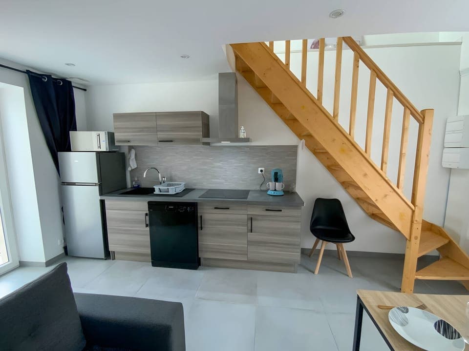 The equipped and fitted kitchen is designed in elegant shades of grey and brown, creating a warm atmosphere. It has a spacious refrigerator to keep food fresh. A modern hob and extractor hood are also installed to facilitate meal preparation.A microwave oven is available to heat dishes quickly. For coffee lovers, a coffee maker is ready to prepare delicious hot drinks. This functional and aesthetic kitchen is the ideal place to cook and share good culinary moments with family or friends.