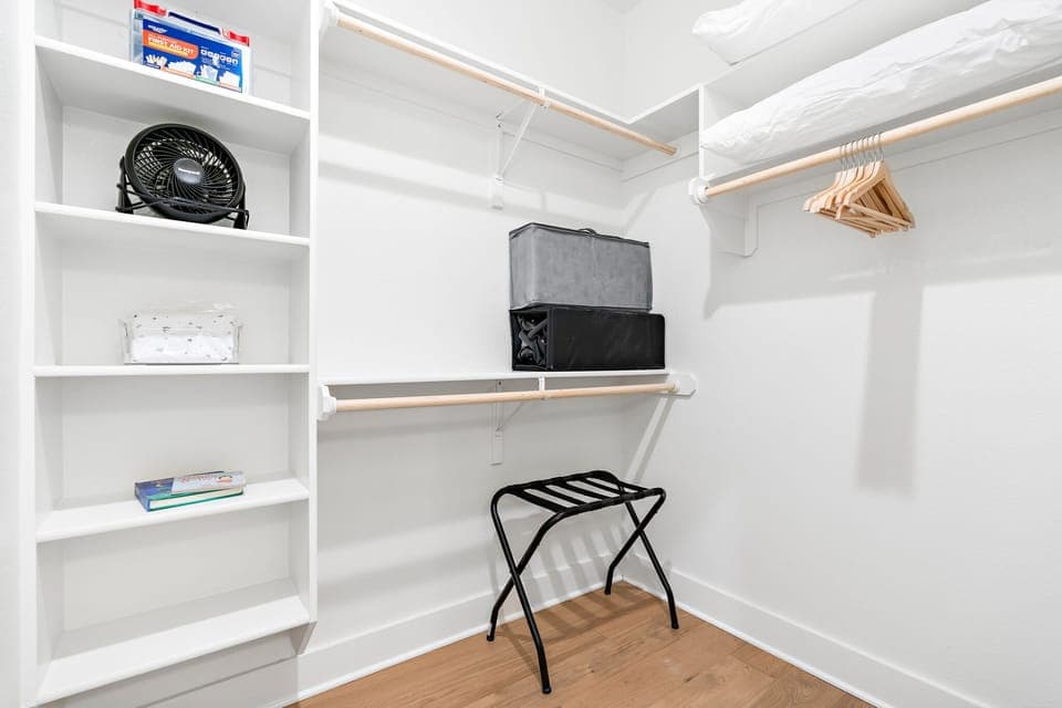 Master walk-in closet hosts the first aid kit, portable fan, packnplay and books