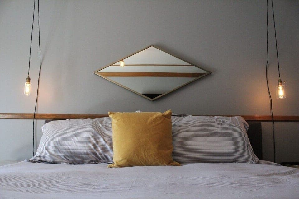 Sink into plush pillows under warm bedside pendant glow.