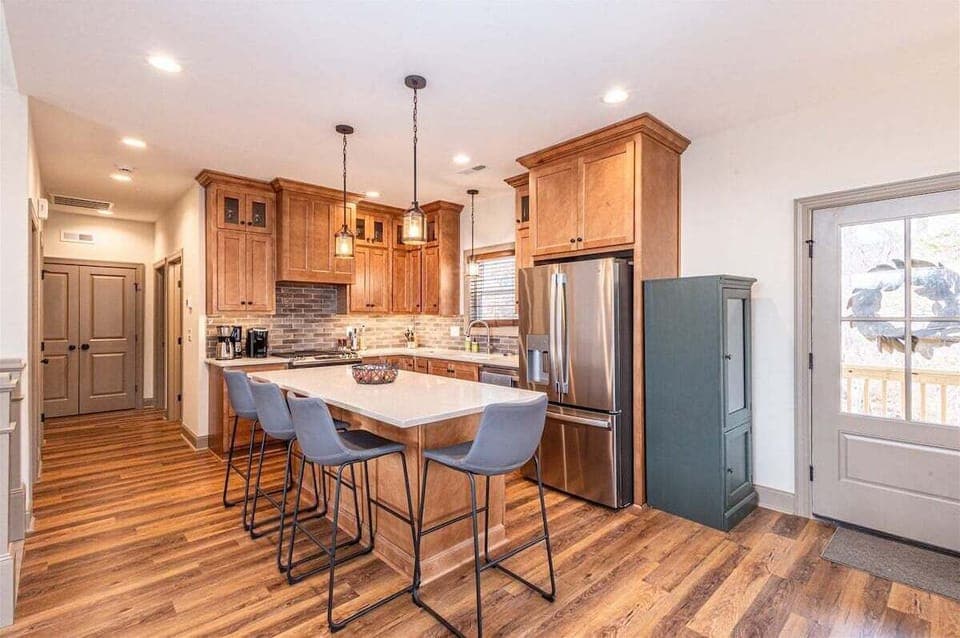 Fully stocked modern kitchen featuring stainless steel appliances, island seating, and stylish finishes.
