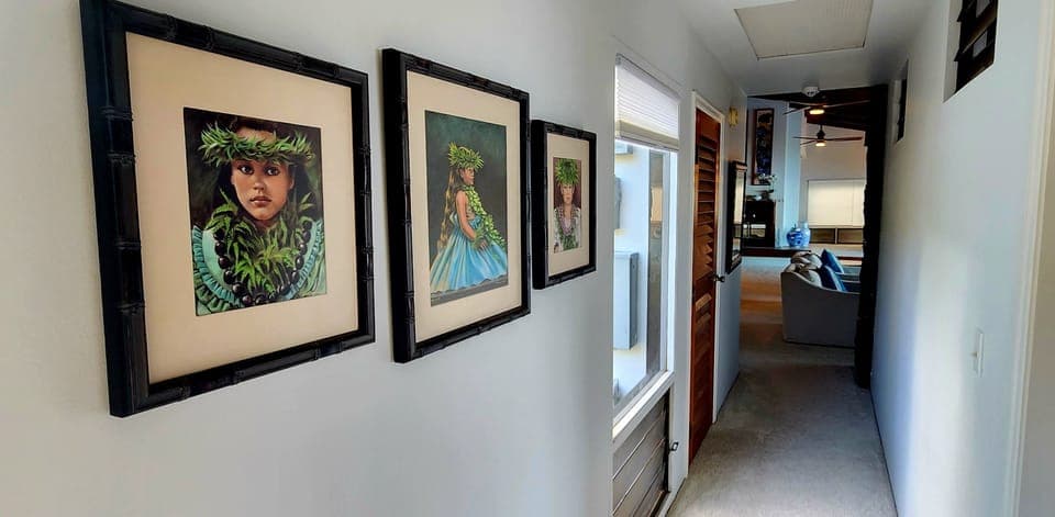 Hallway from primary and guest bedrooms on the main floor looking into living area and kitchen.  Beautiful artwork may be enjoyed throughout the house.