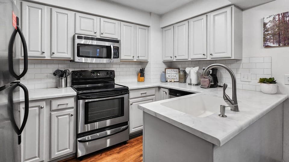 Kitchen: Well-equipped kitchen, stainless steel appliances, white counter and cabinets, range of basic cookware
