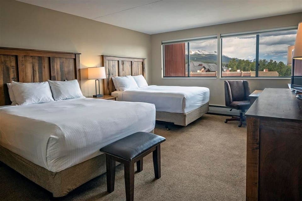 Spacious hotel room with two queen beds and scenic mountain views.